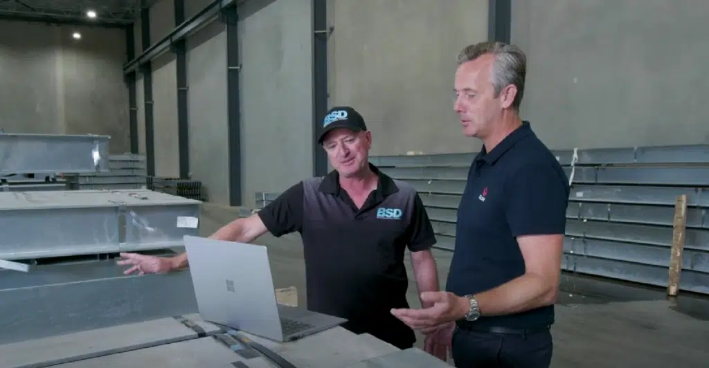 Two men looking at a laptop screen discussing trade finance in the manufacturing industry